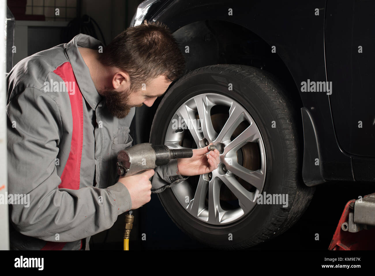 Mechanic using a tire pistol on a car wheel Stock Photo