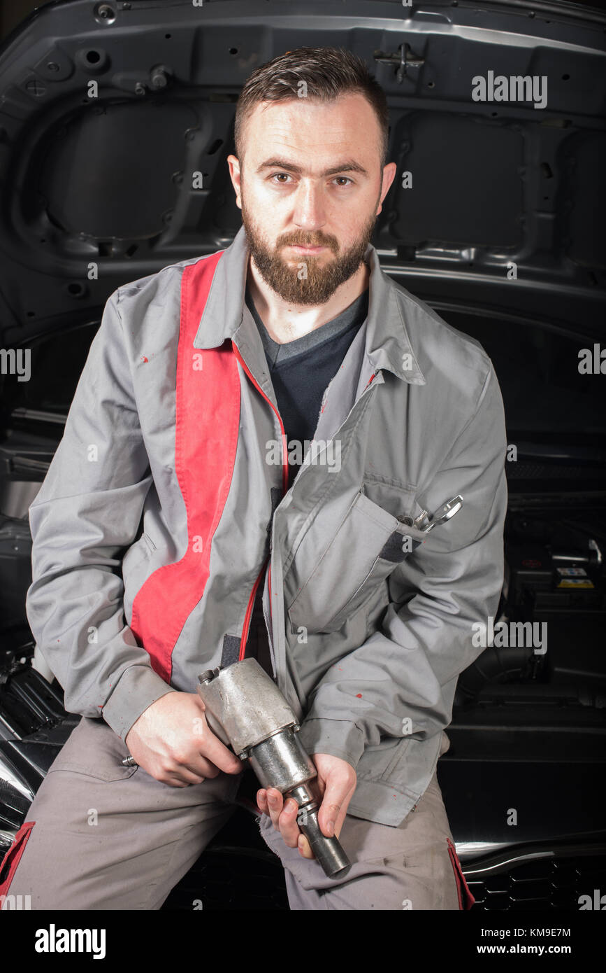 Portrait of a mechanic holding a tire pistol Stock Photo