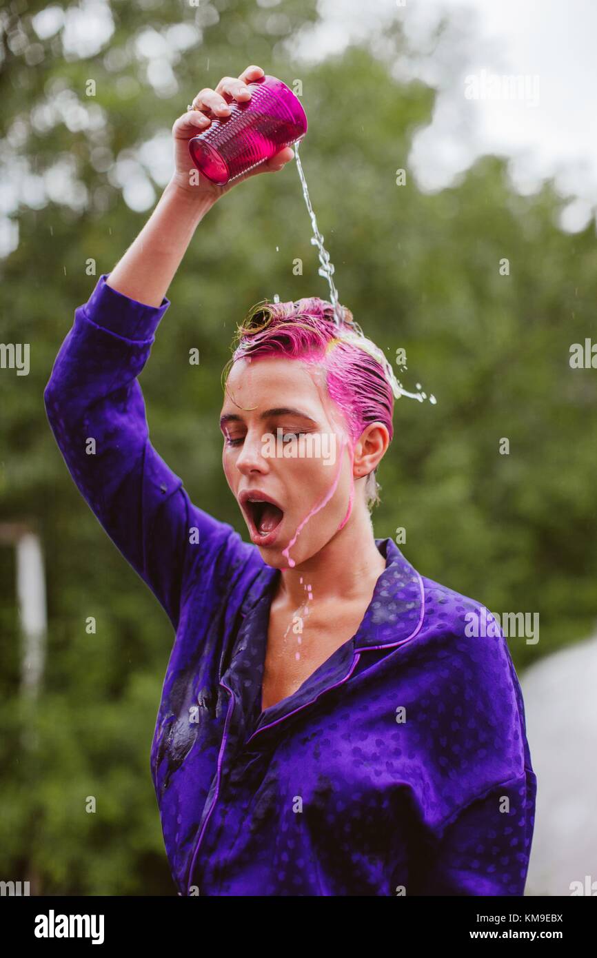 Woman with pink hair pouring a glass of water over her head Stock Photo -  Alamy