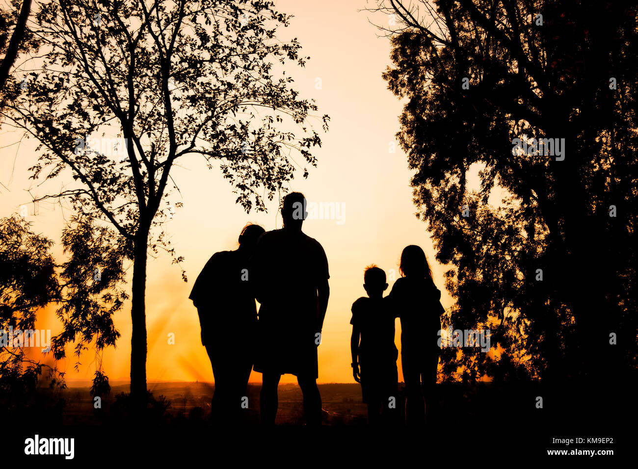 Silhouette of a family with two children holding hands at sunset Stock Photo