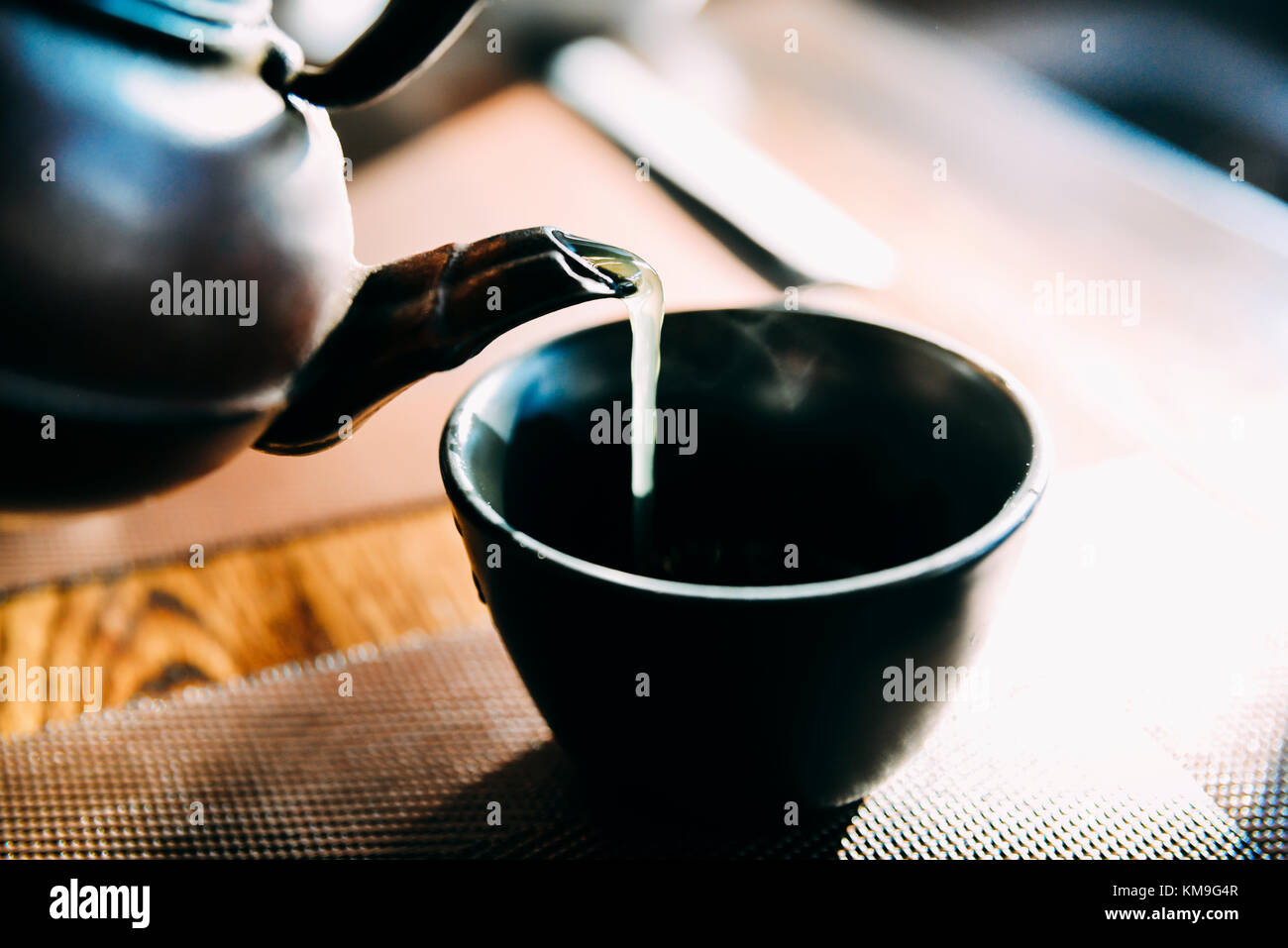 Close up pouring a hot Japanese green tea kettle on an oriental style