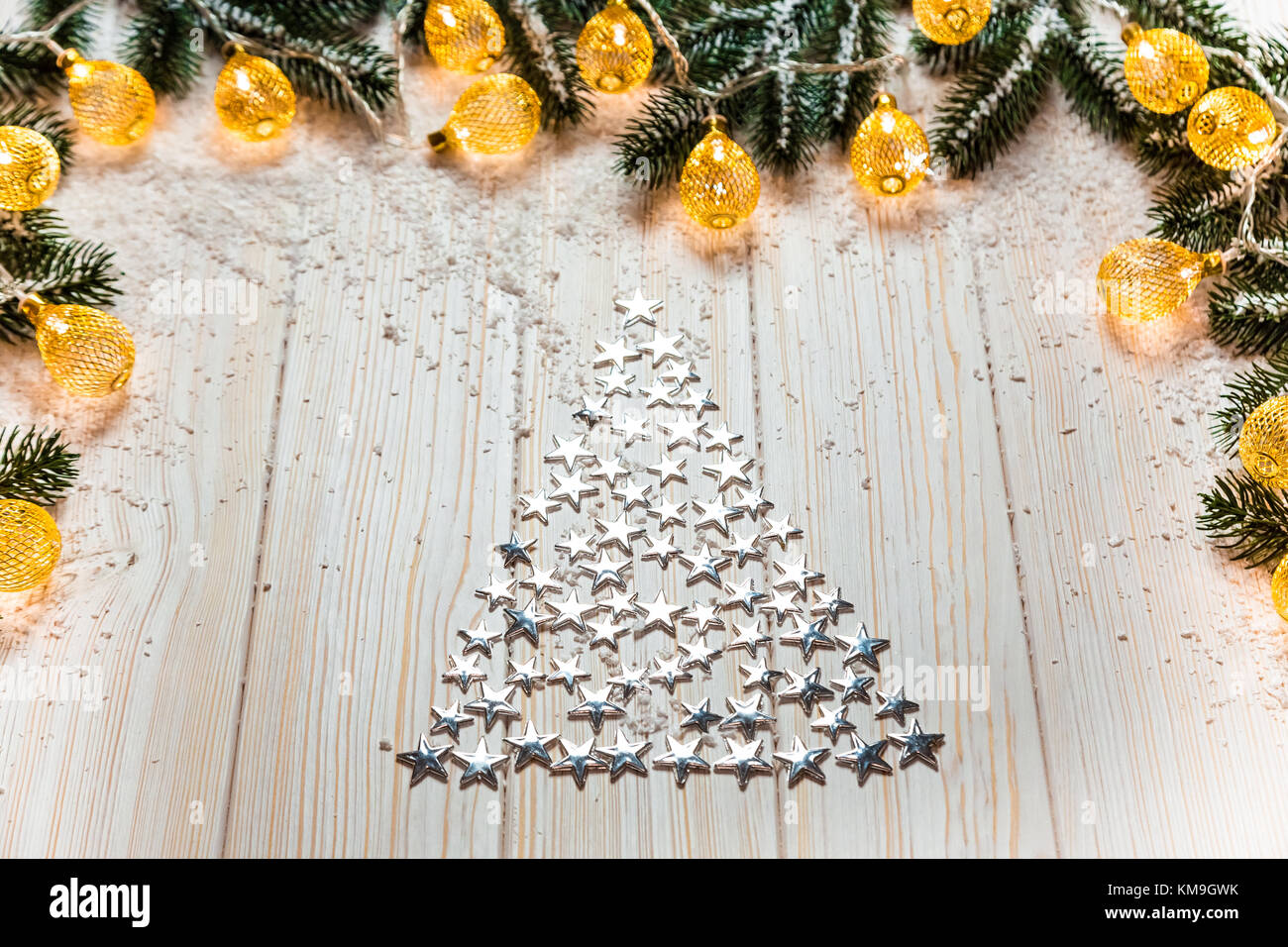 Christmas tree of silvery stars on a white wooden background with snow ...