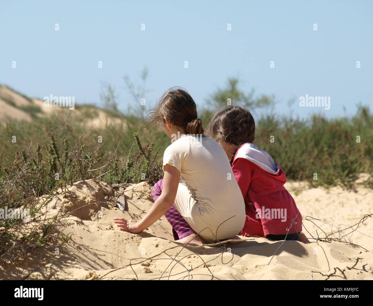 2 girls playing with the sand on a sand dune Stock Photo