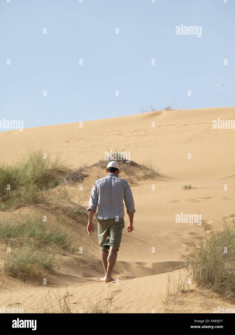 man walking in the desert on a sand dune Stock Photo
