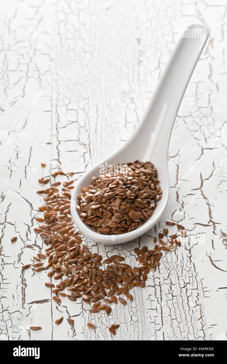Raw, unprocessed linseed or flax seed in scoop on white table background Stock Photo