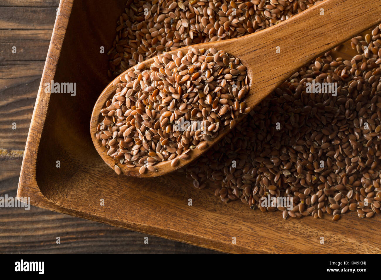 Raw, unprocessed linseed or flax seed in wooden scoop on wood table background Stock Photo