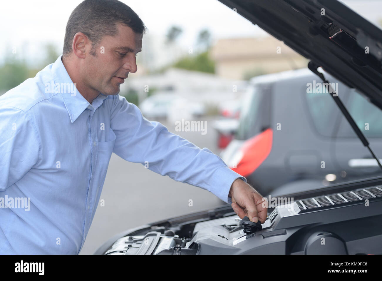 man putting car oil to his car Stock Photo Alamy