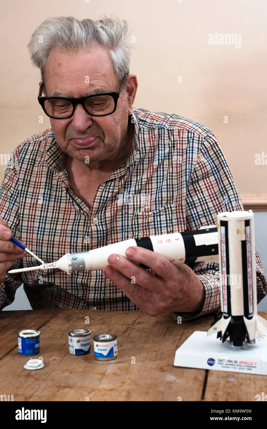 Elderly man making a Airfix model of the Apollo 7 space rocket Stock Photo