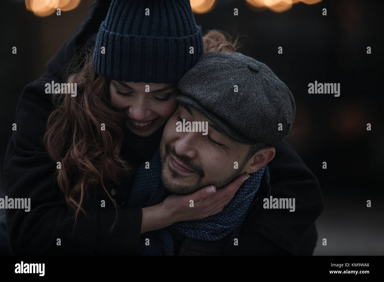 Young couple having fun outdoors at winter fair. Wearing warm clothes, hats and scarfs. Visiting christmas market in Vienna, Austria. Everything is de Stock Photo