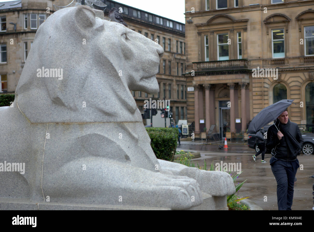 cenotaph lion statue sculpture woman with umbrella  Dark rainy day as people shop through the city Stock Photo