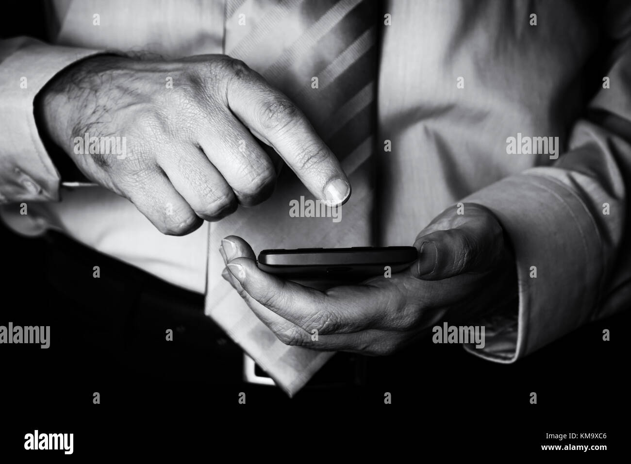 Man holding and touching screen or display with finger of a mobile phone, cell phone or smartphone. Male businessman typing a message or browsing the  Stock Photo