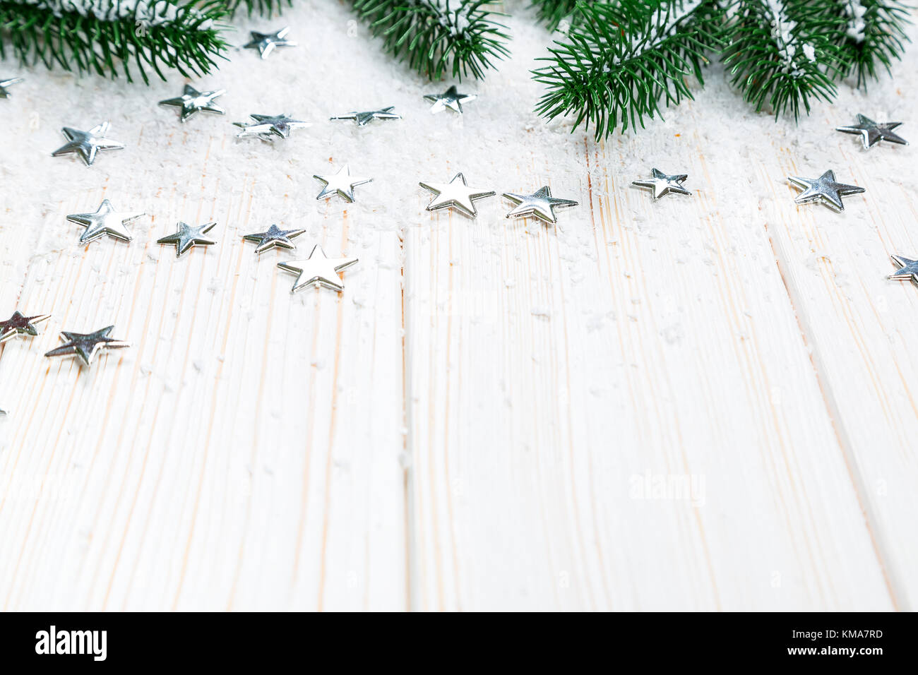Christmas fir tree in snow with silver stars on white wooden background ...