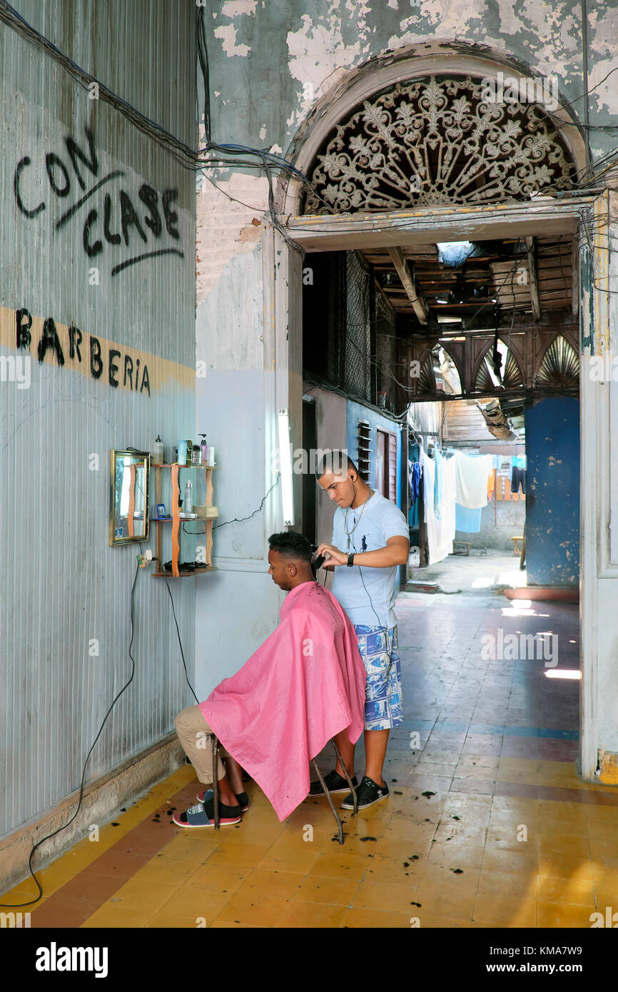 Barber who has set up shop in a residential lobby, Santiago de Cuba, Cuba Stock Photo