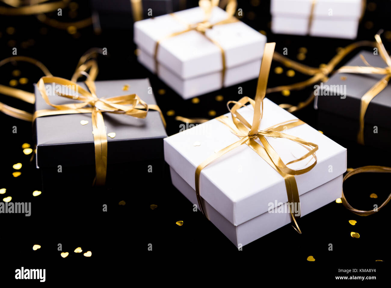 Black and white gift boxes with gold ribbon on shine background. Close