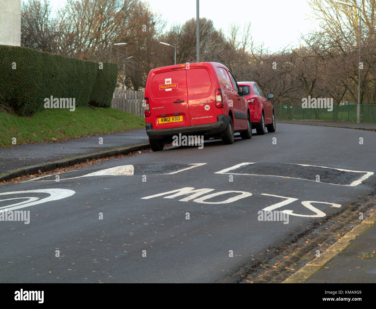 red royal mail post office van with ironic slow road marking sign parked on the street Stock Photo