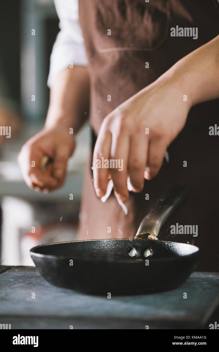 The cook adds spices and onion to food Stock Photo - Alamy