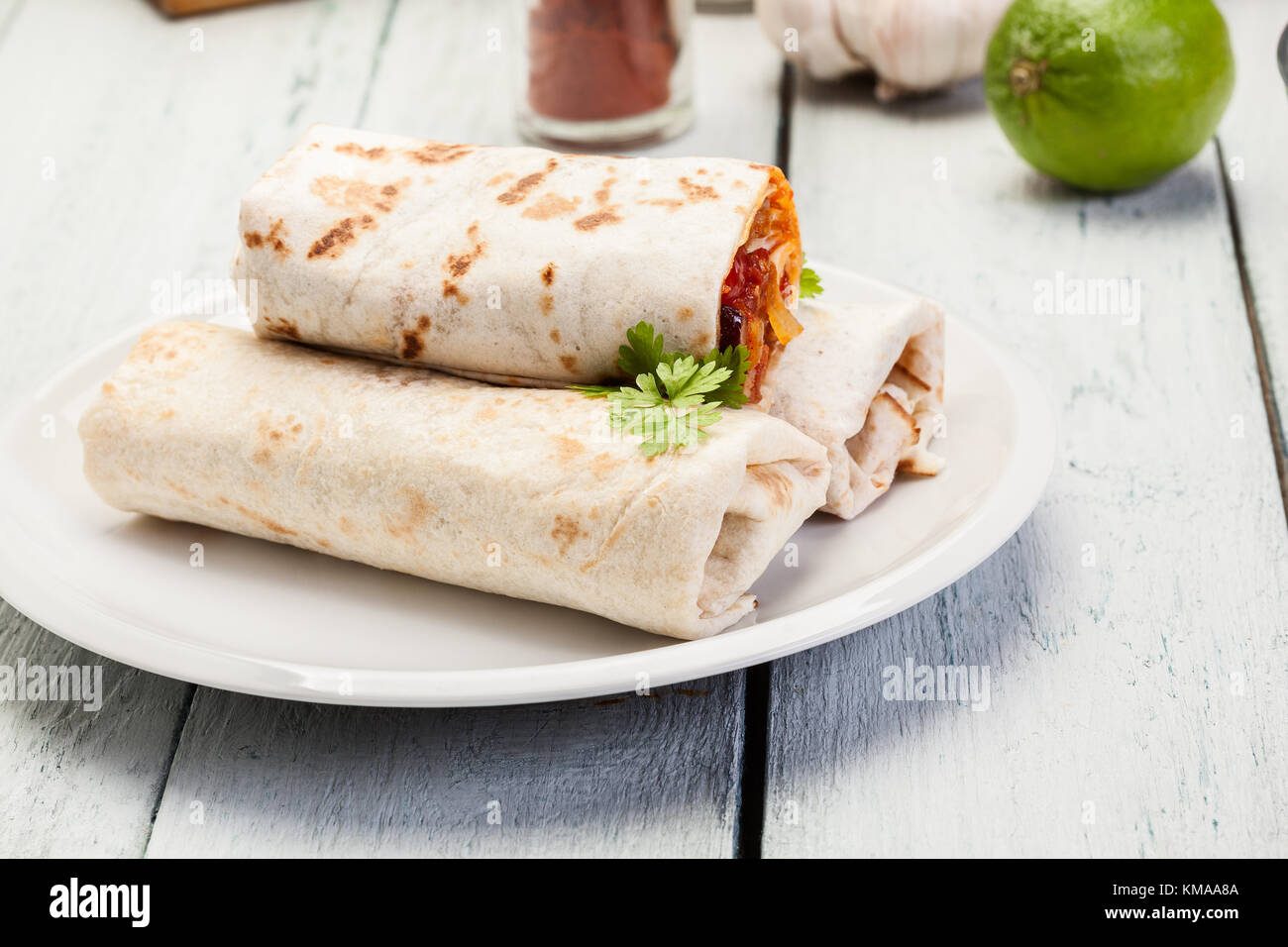 Mexican burritos wraps with mincemeat, beans and vegetables on a plate