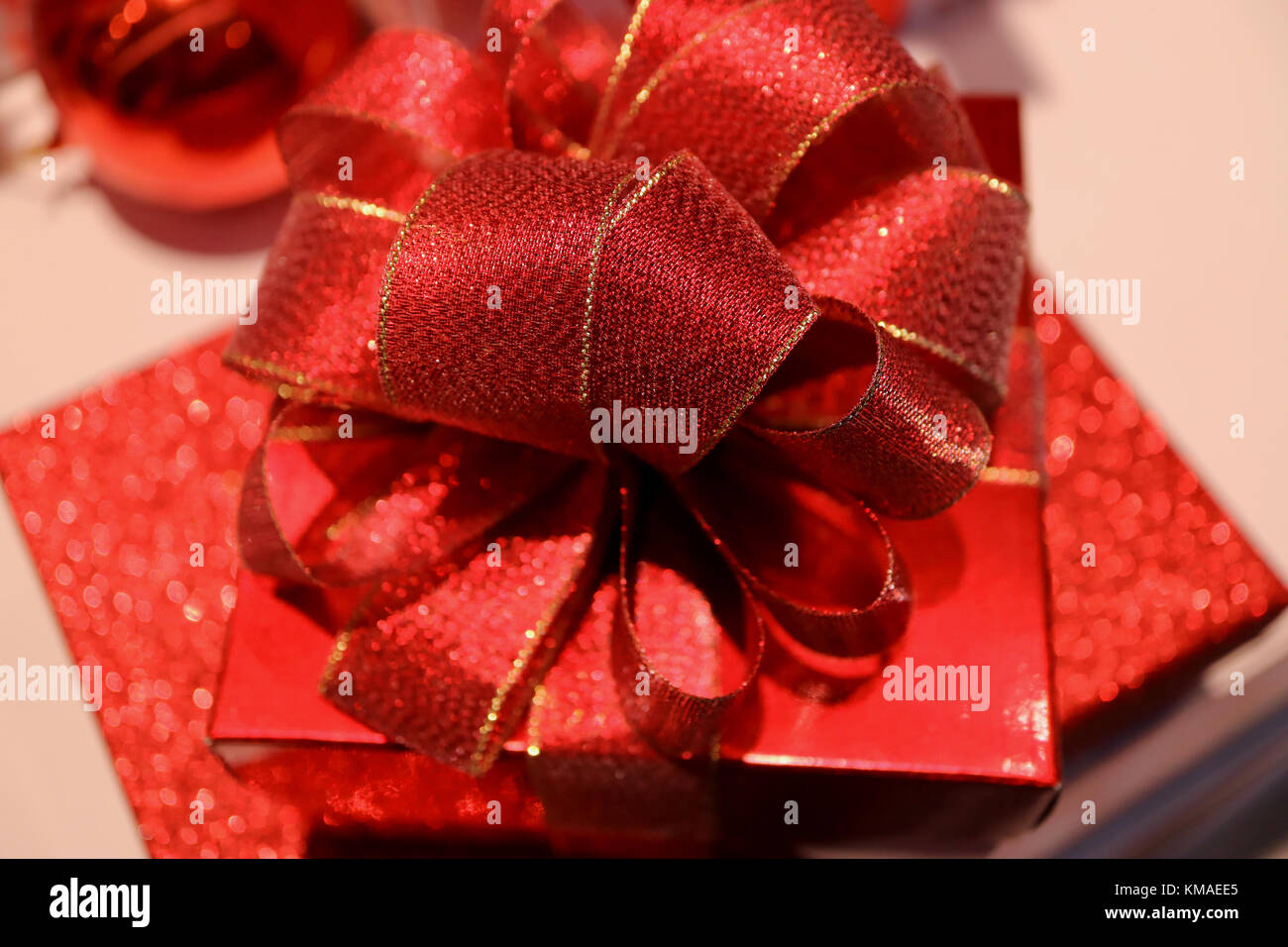 Closed up a square shiny red gift box with gritter red ribbon bow ...