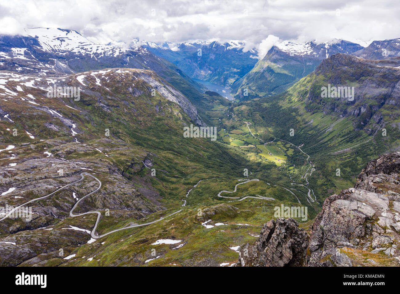 Spectacular view to Geirangerfjord with road snaking down through the valley all the way to the cruiseship Stock Photo