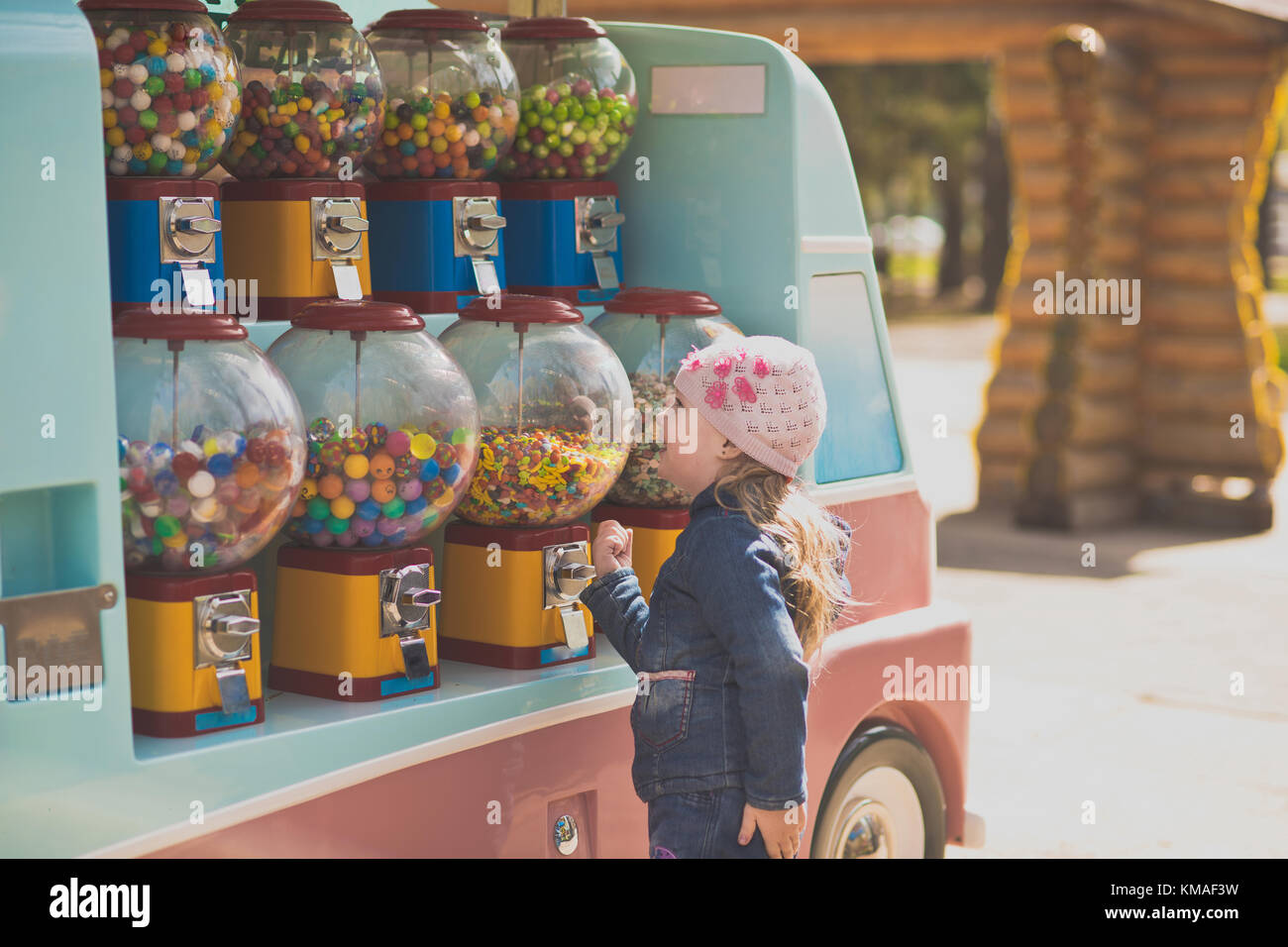 The little girl stopped in front of a battery of machines for the sale of small sweets. Genuinely enjoys opportunities to choose any treat Portrait of Stock Photo