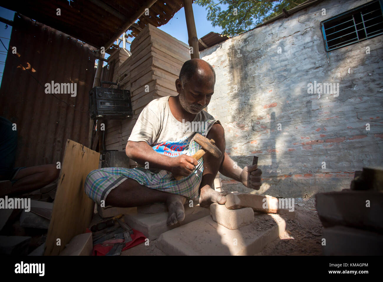 A craftsman (Nirojon Sarkar, Age 55) is busy mending traditional stone grinder, popularly known as Sheel-Pata, in Dhaka, Bangladesh. Stock Photo