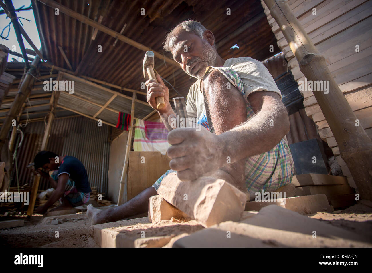 A craftsman (Nirojon Sarkar, Age 55) is busy mending traditional stone grinder, popularly known as Sheel-Pata, in Dhaka, Bangladesh. Stock Photo
