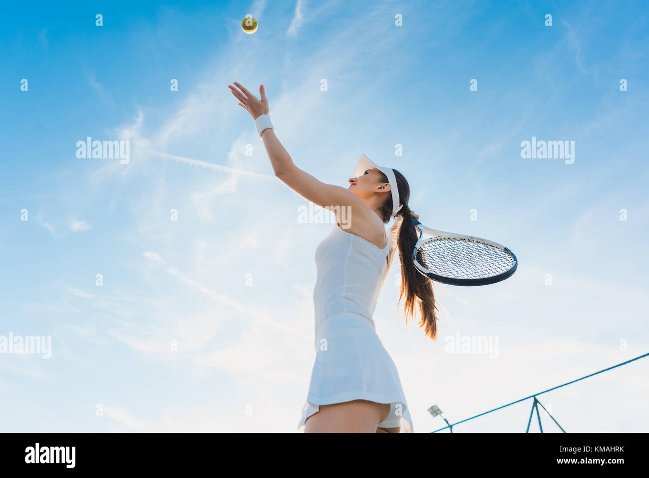 Woman playing tennis giving service Stock Photo