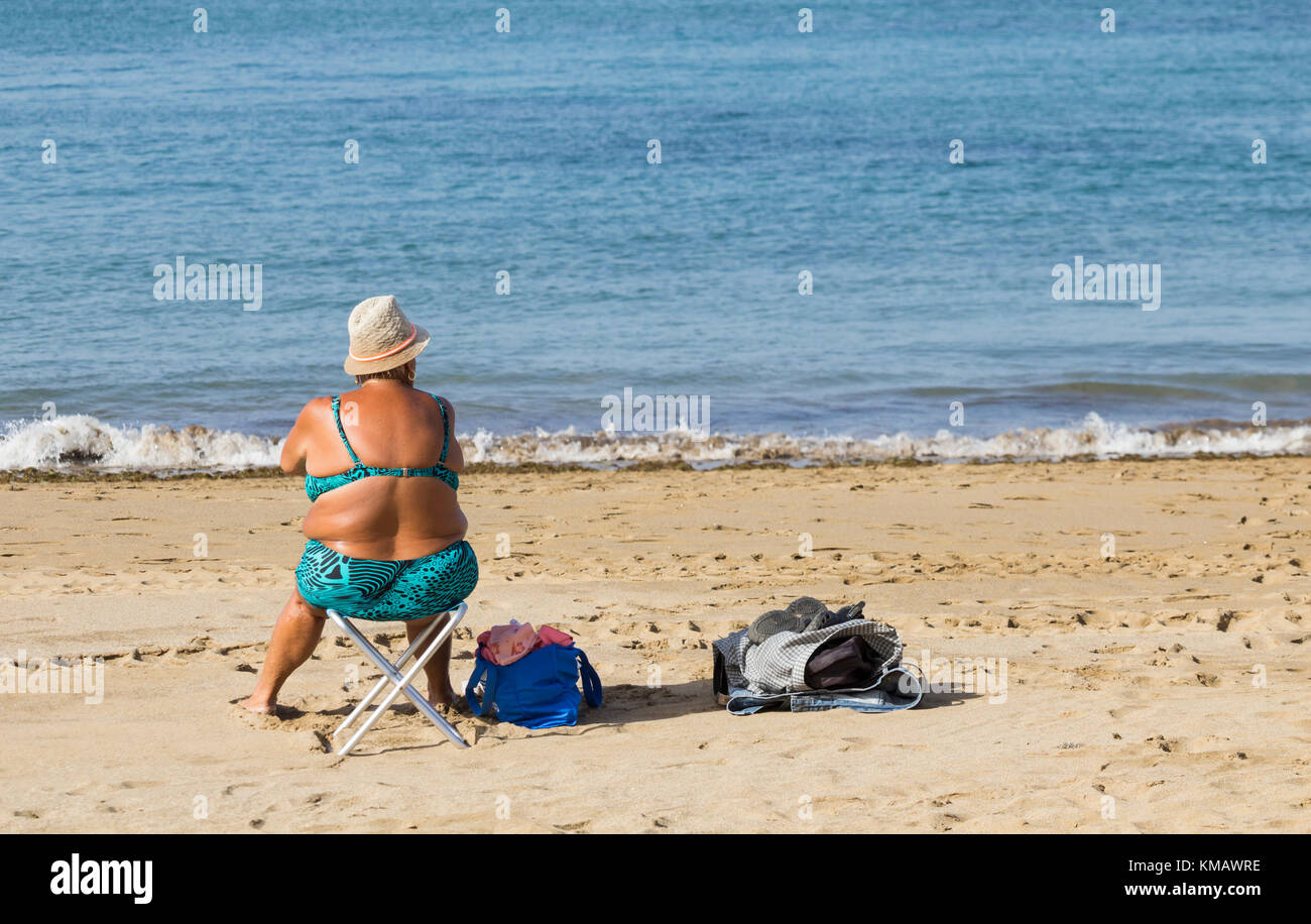 Rear view of elderly woman in bikini on beach in Spain Stock Photo