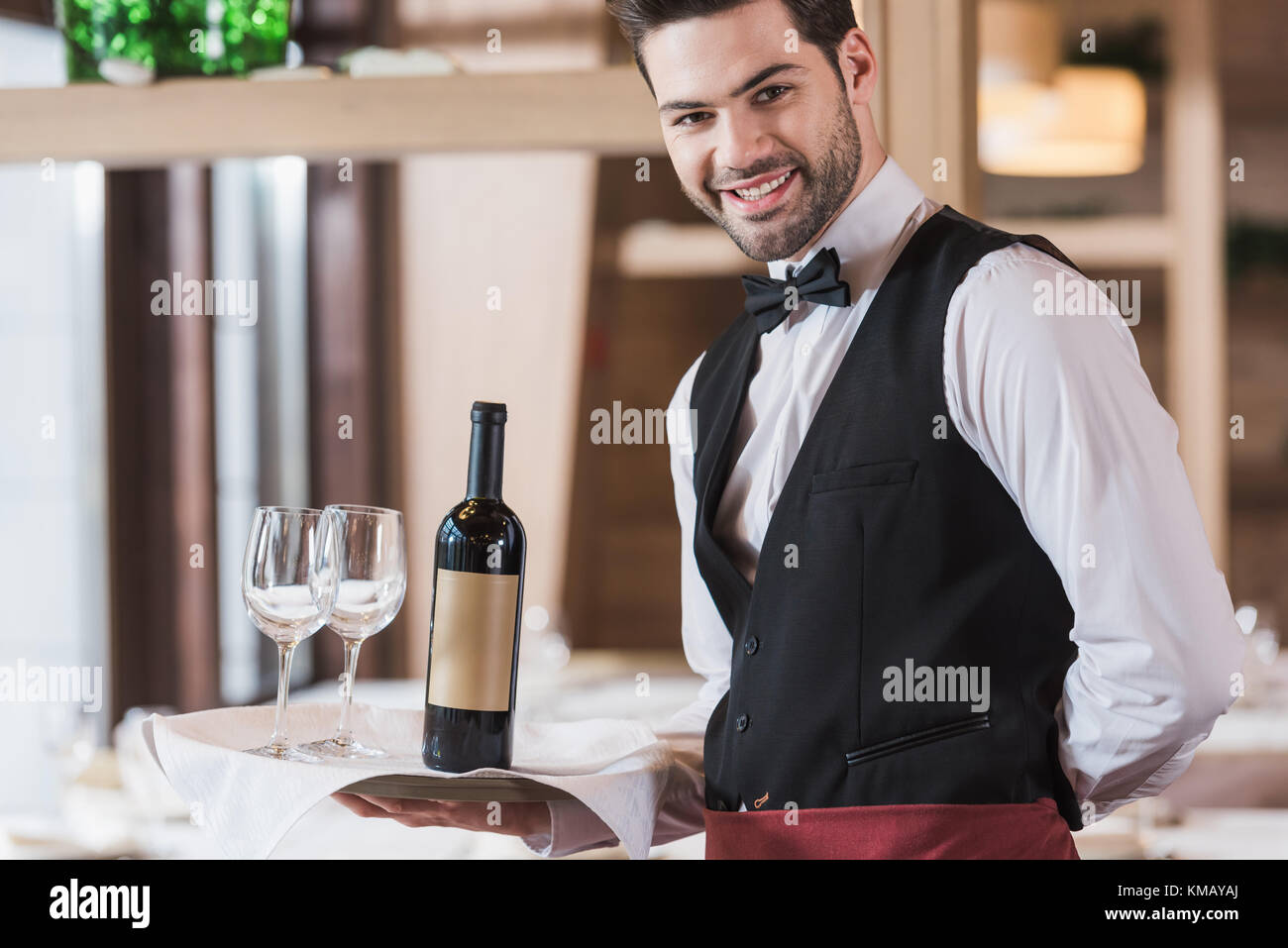 Waiter holding tray with wineglasses and bottle Stock Photo - Alamy