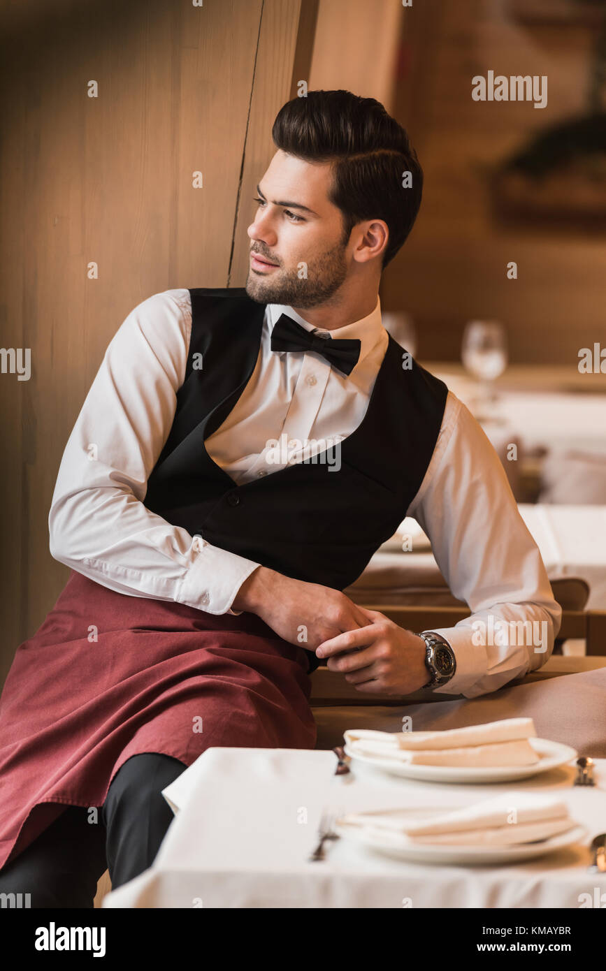 Waiter leaning on chair Stock Photo