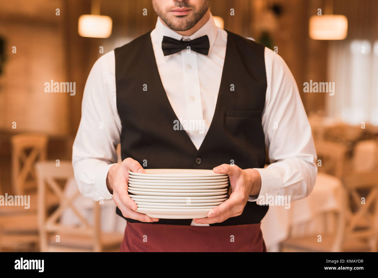 Waiter holding pile of plates  Stock Photo