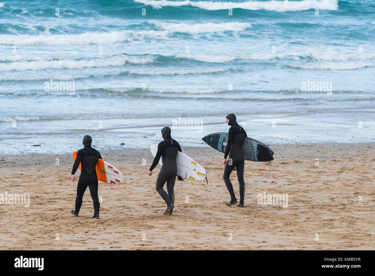 Surfing Cornwall - three surfers walking on Fistral Beach Newquay Cornwall UK. Stock Photo