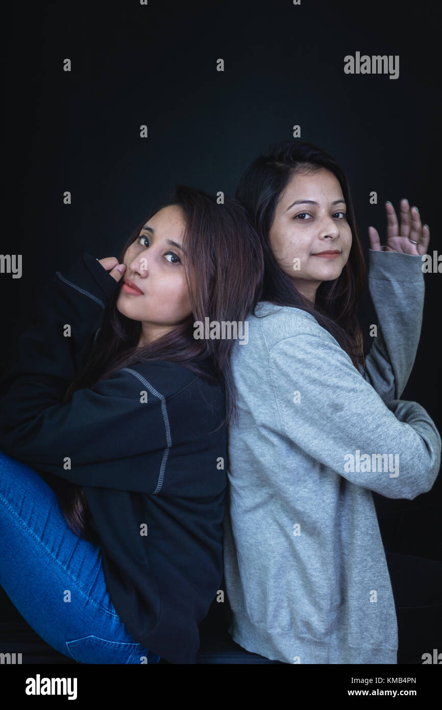 Two young girls sitting with their back pressed together. Stock Photo