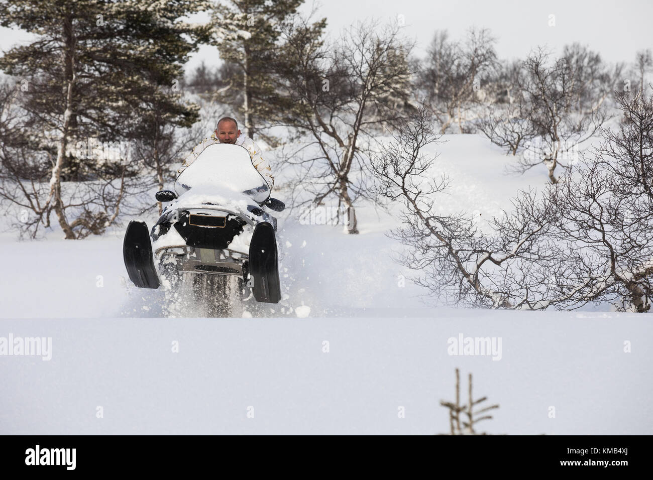 Adult man playing and jumping with a snowmobile in the snow on the ...