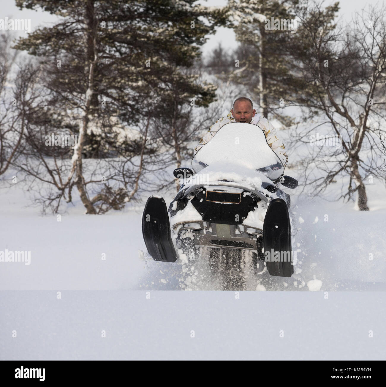 Adult man jumps with a snowmobile in the snow on the mountain in Norway ...