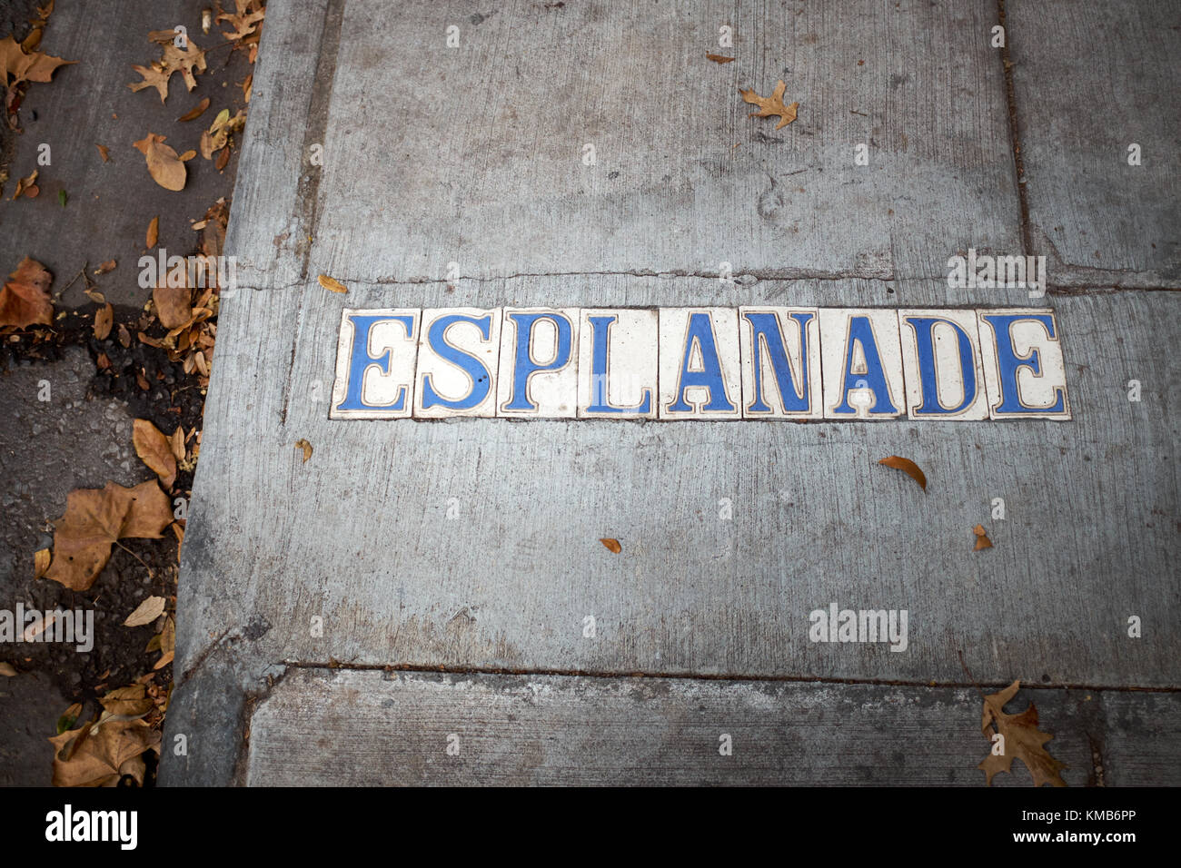 Esplanade place in blue and white letters name set into a concrete sidewalk with fallen dead brown autumn leaves Stock Photo