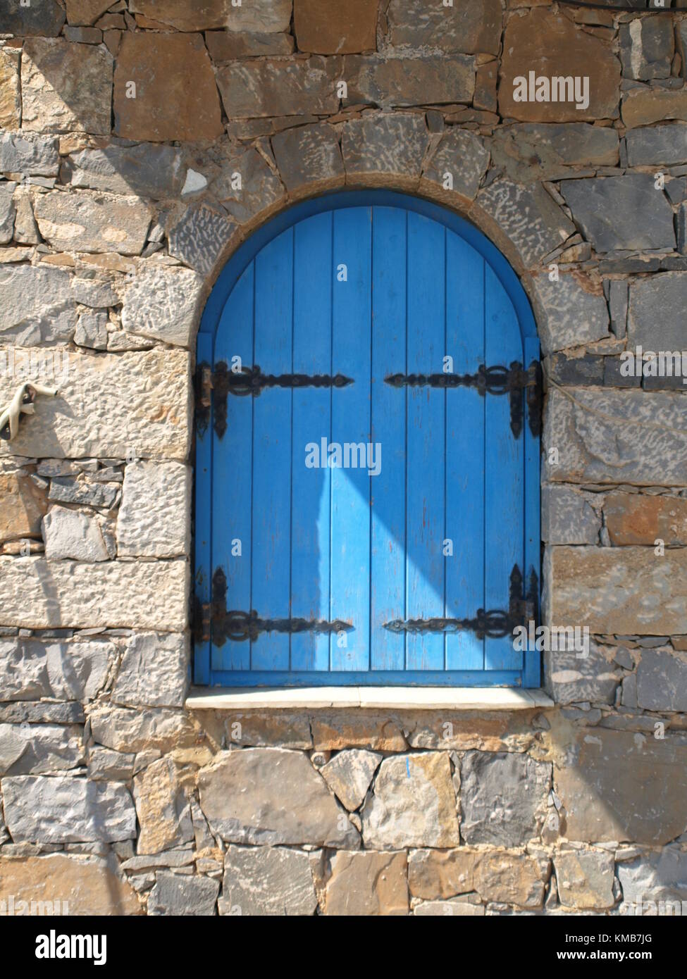 Old wooden window set in old stone wall. the picture was taken in Elunda island while  traveling Crete Greece. Stock Photo