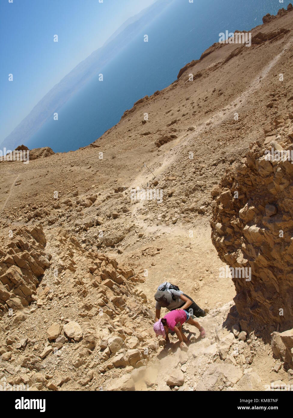 mother and child going uphill a mountain with the sea on the background Stock Photo