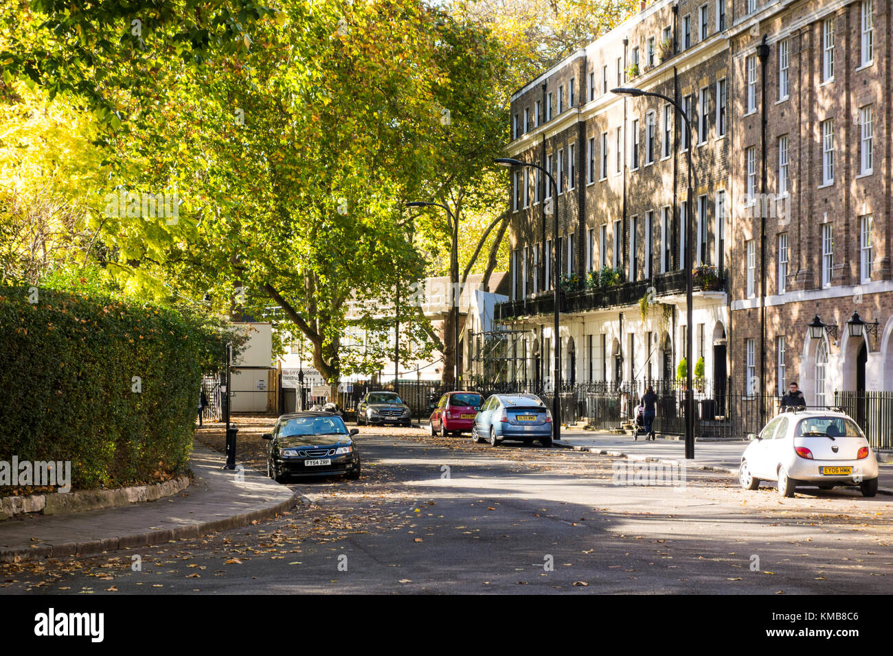 Early autum / fall / autumnal scene in Mecklenburgh Square with green trees and fallen leaves. Terraced houses designed by Joseph Kay. Bloomsbury, Lon Stock Photo