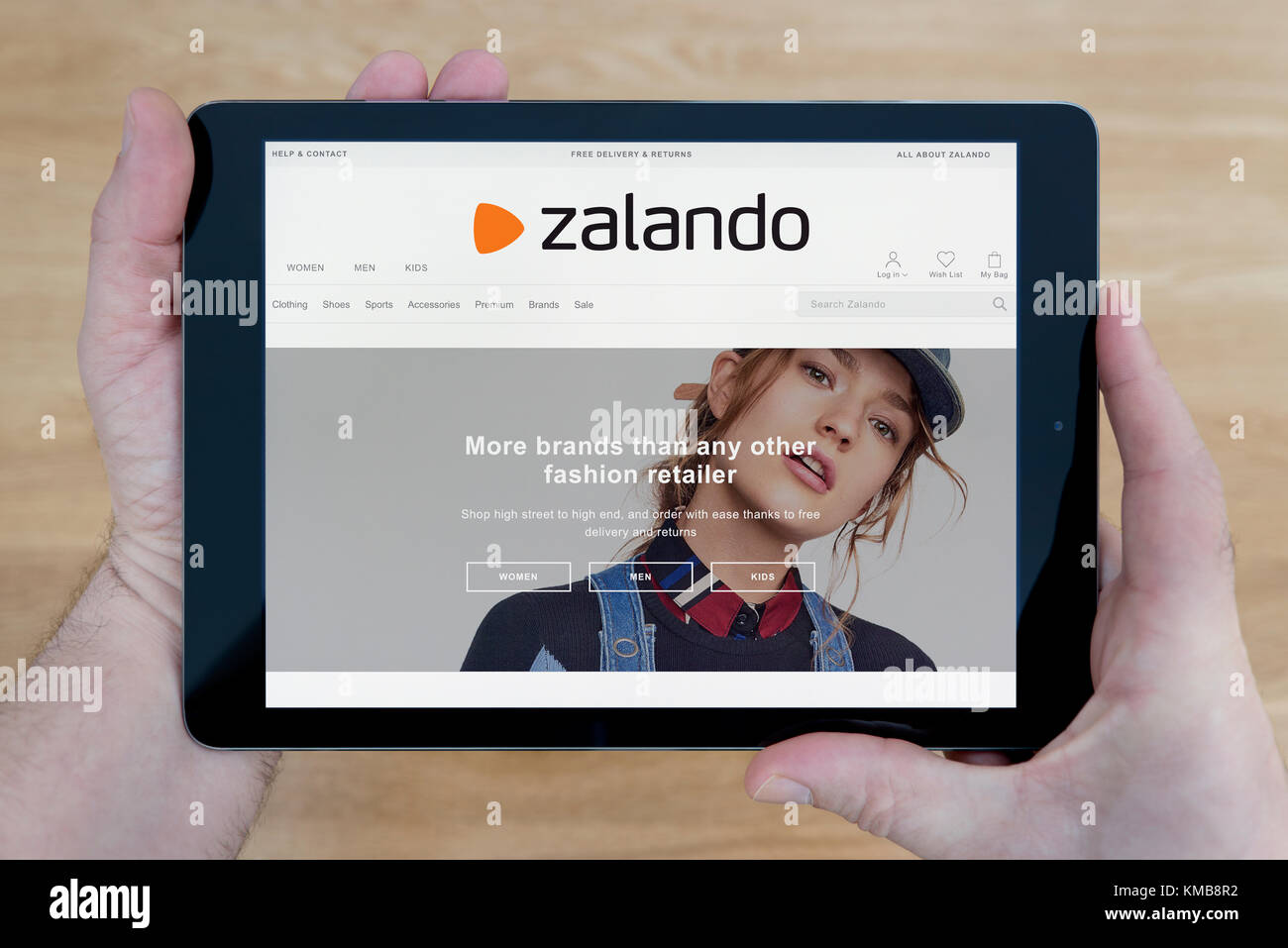 A man looks at the Zalando website on his iPad tablet device, shot against  a wooden table top background (Editorial use only Stock Photo - Alamy