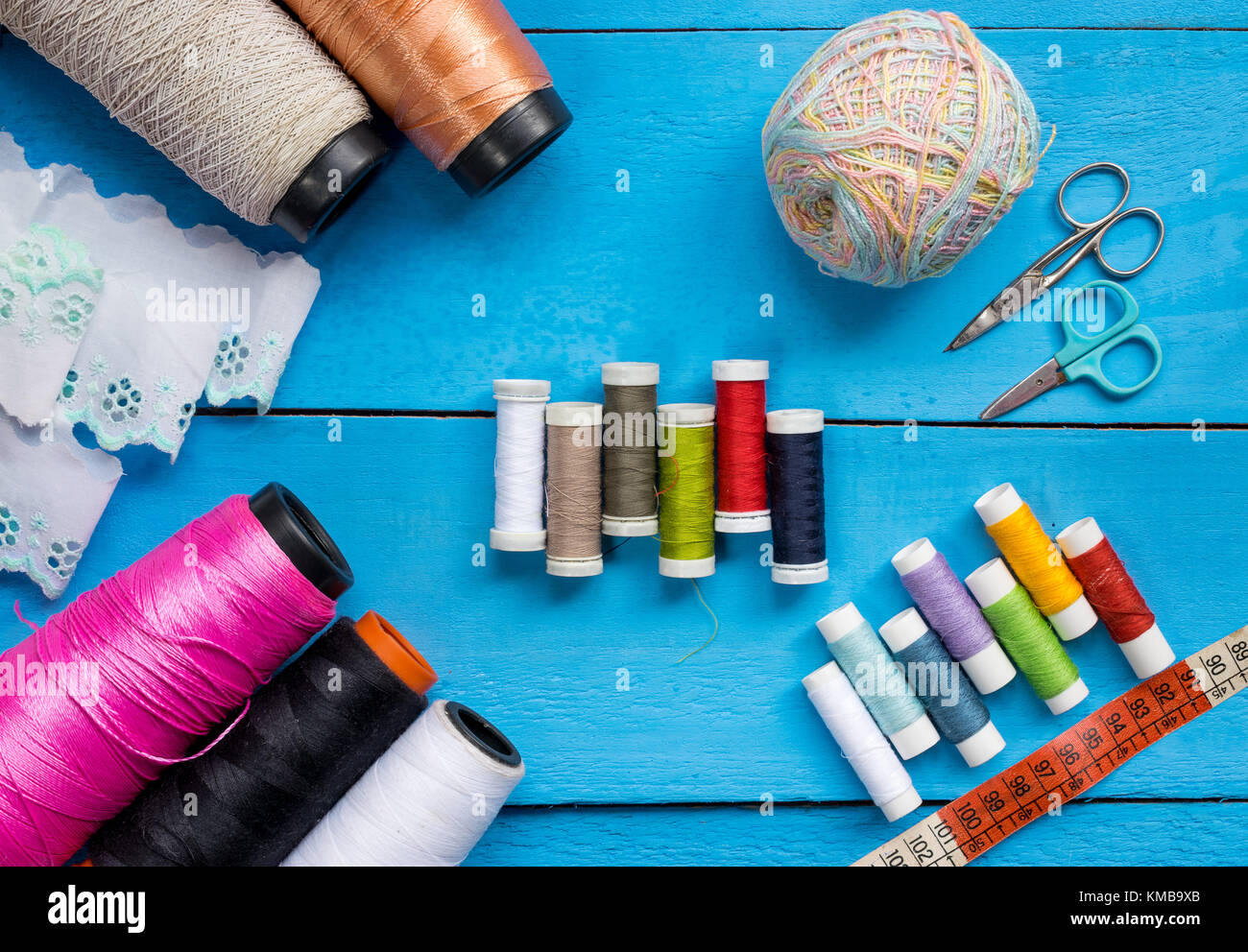 Sewing items - thimble, needle, measuring tape, spools of blue thread,  including pins. Blue fabric for sewing on background Stock Photo - Alamy