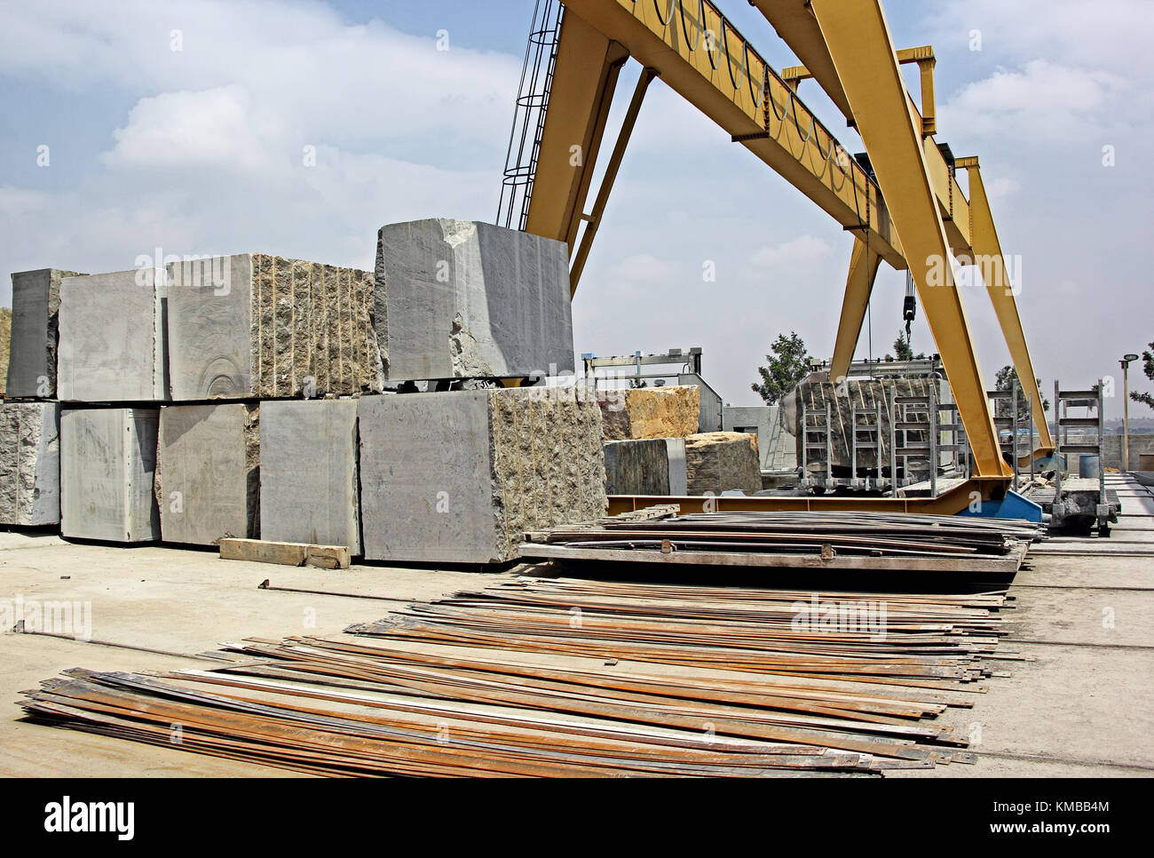 Heavy natural granite stone blocks stacked for processing into floor and wall tiles and slabs by cutting and polishing with the help of gantry crane Stock Photo