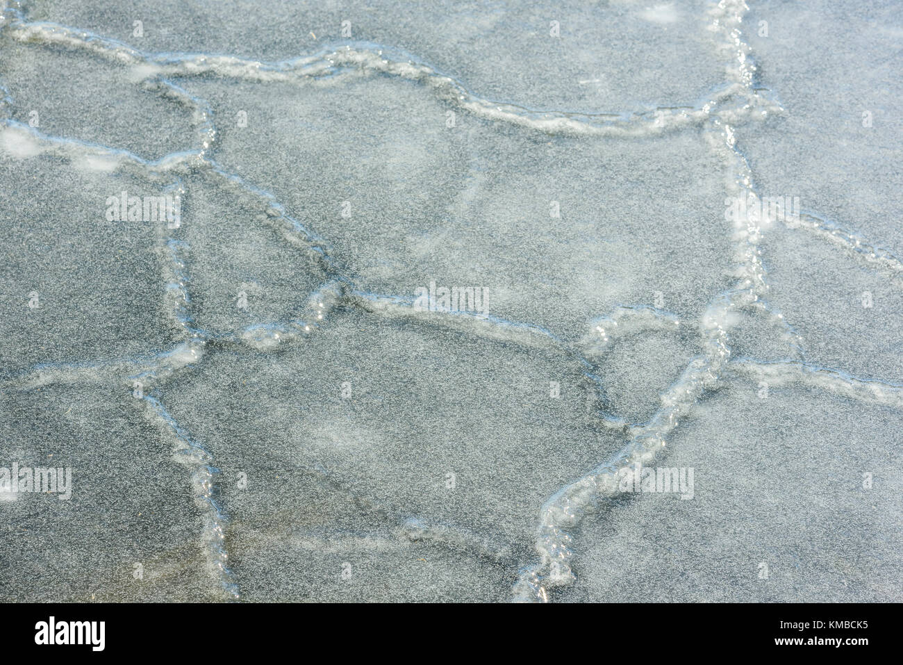Broken up ice sheets have refrozen and formed a larger slab of ice making a pattern with seams and small bubbles. Stock Photo
