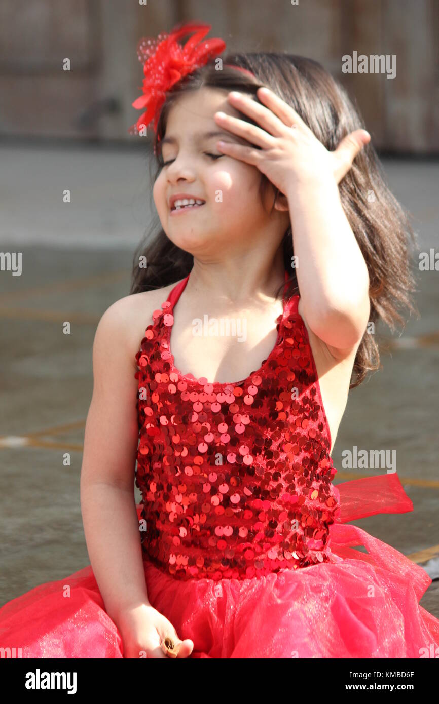 cute girl sitting in red dress beautiful kid in summer Stock Photo
