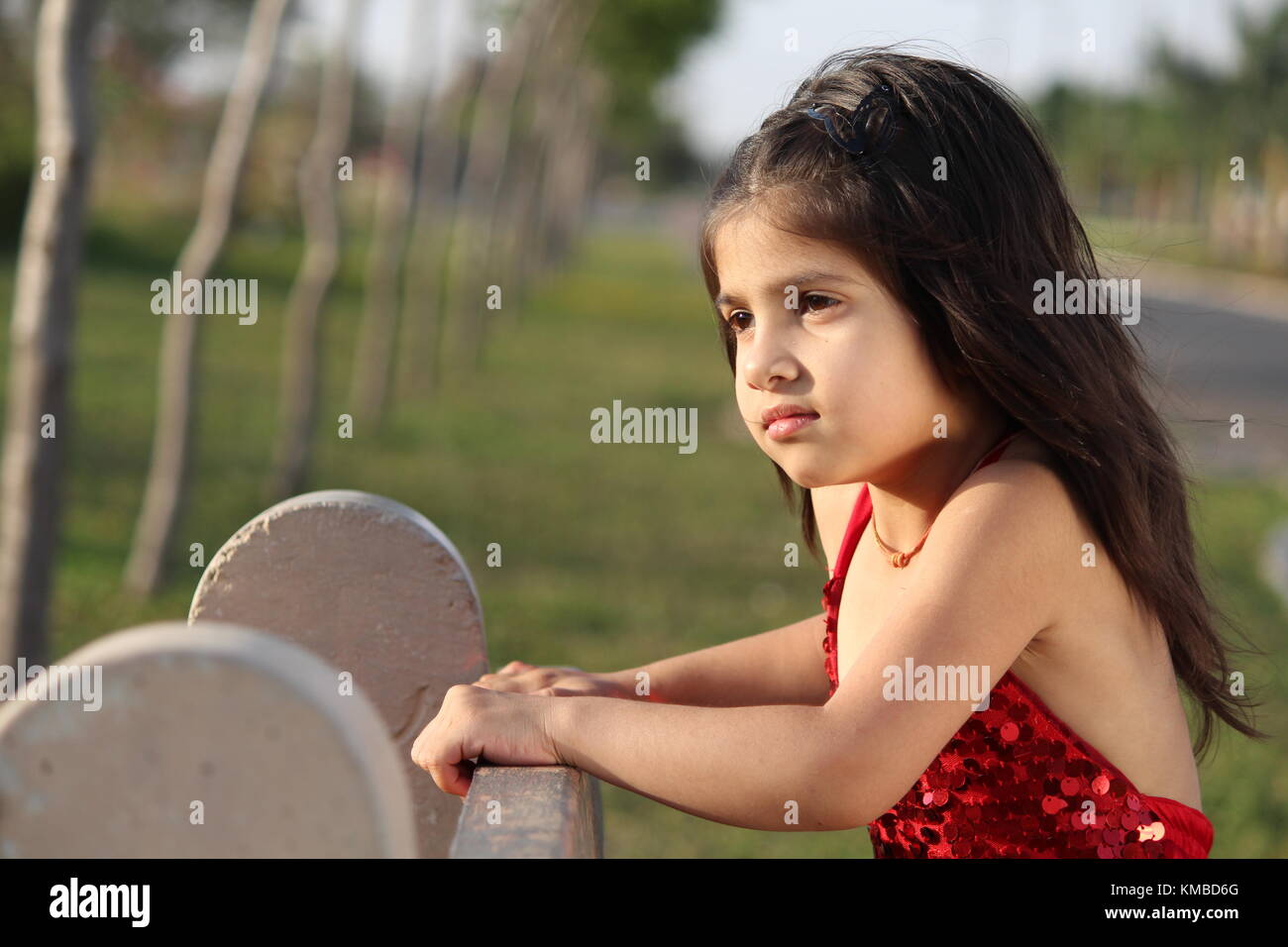 cute girl sitting in red dress beautiful kid in summer Stock Photo