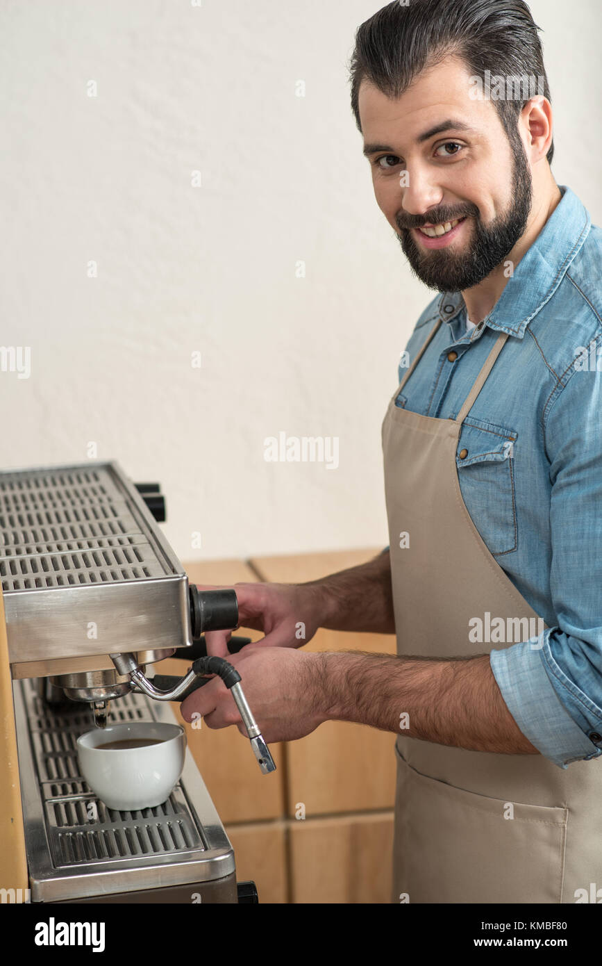 Cheerful young man making coffee while being at work Stock Photo Alamy