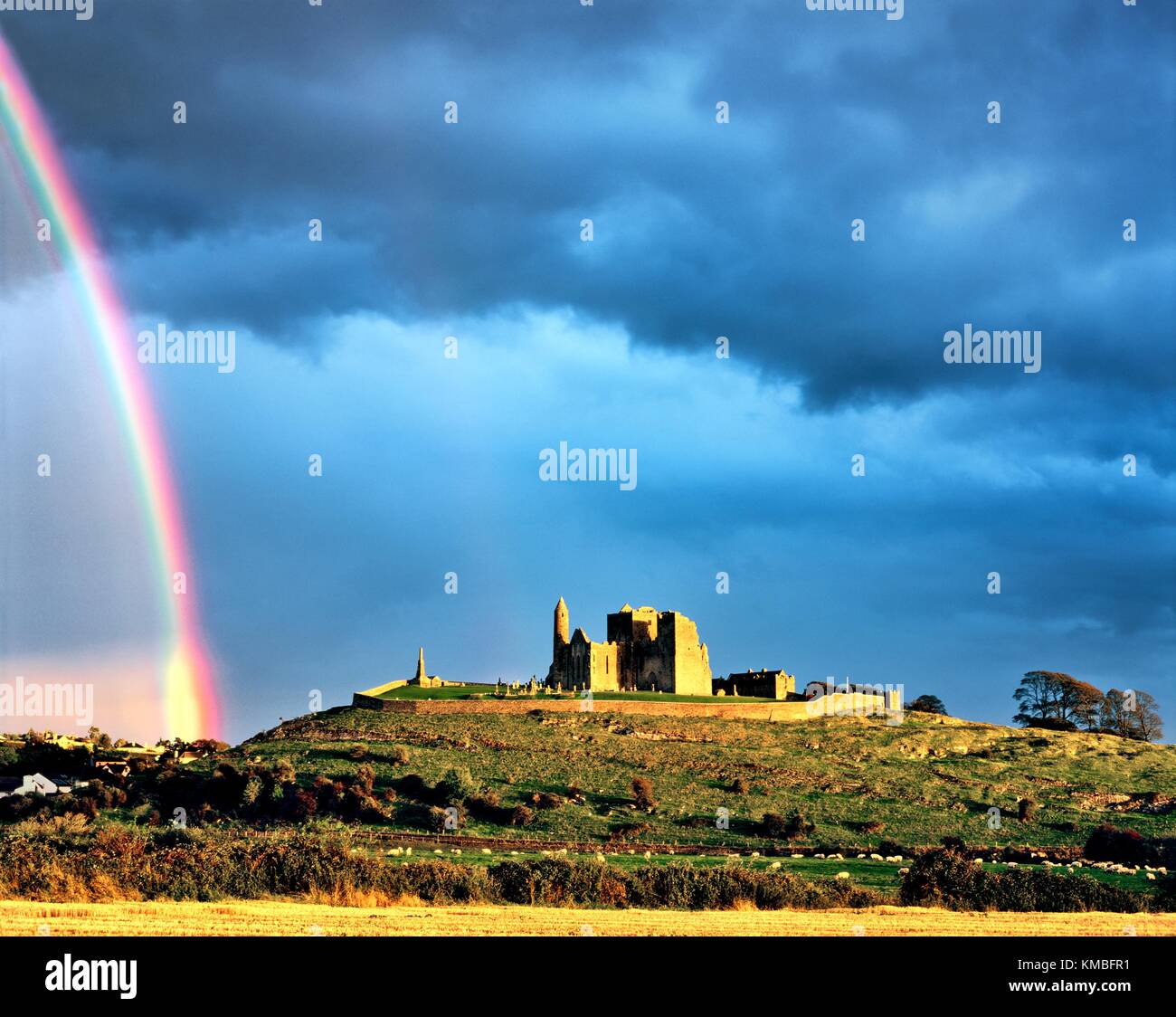 Mediaeval cathedral, round tower and Cormac’s Chapel sit on the Rock of Cashel, County Tipperary, Ireland. Sunlit with rainbow. Stock Photo