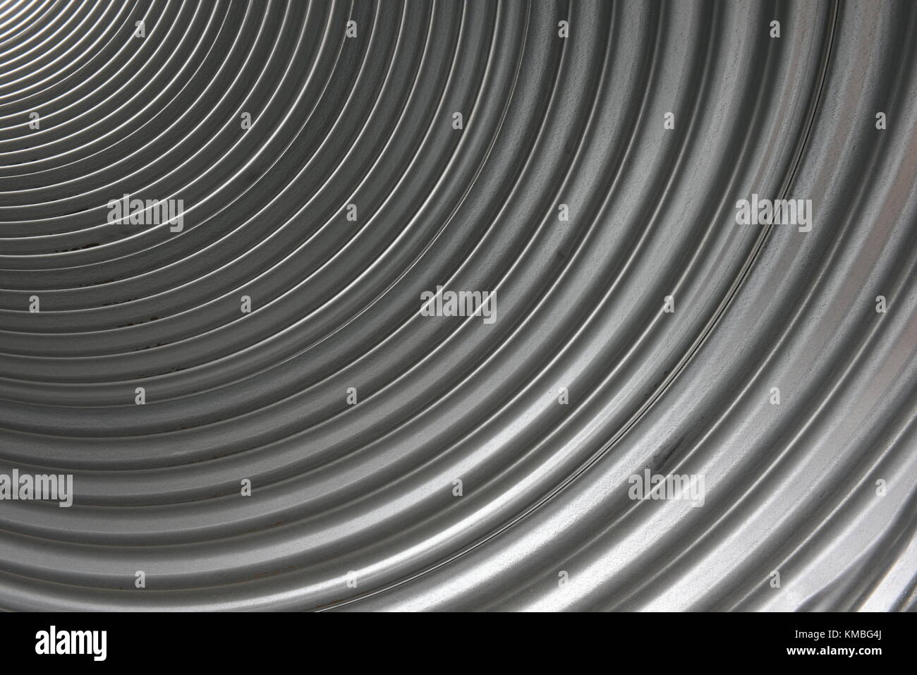 Inside of a corrugated aluminum metal pipe with a pattern of curved lines and textures Stock Photo