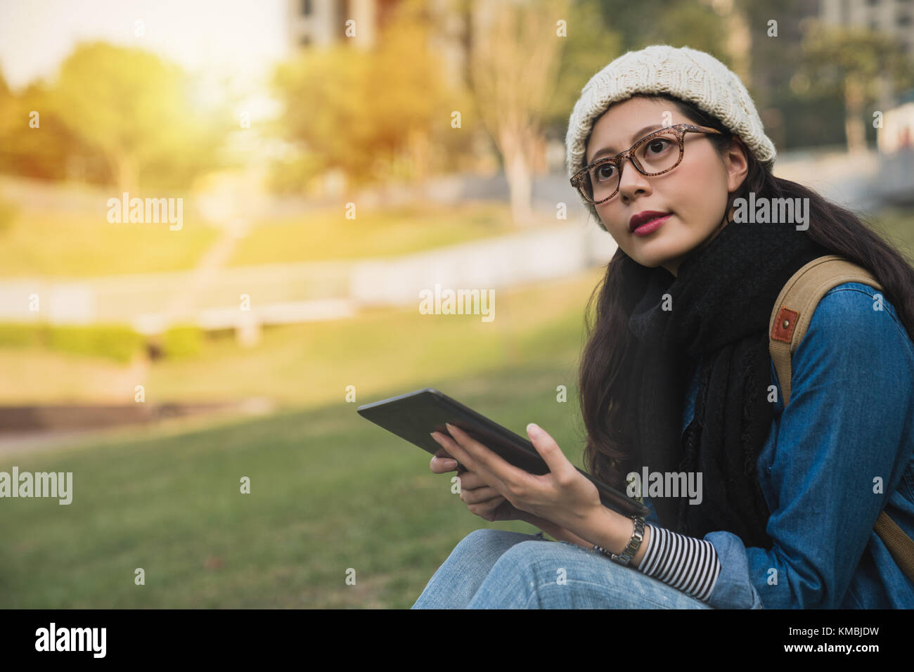 beautiful girl using the e-learning ebook with digital tablet and look away in winter park on a sunny day. Stock Photo