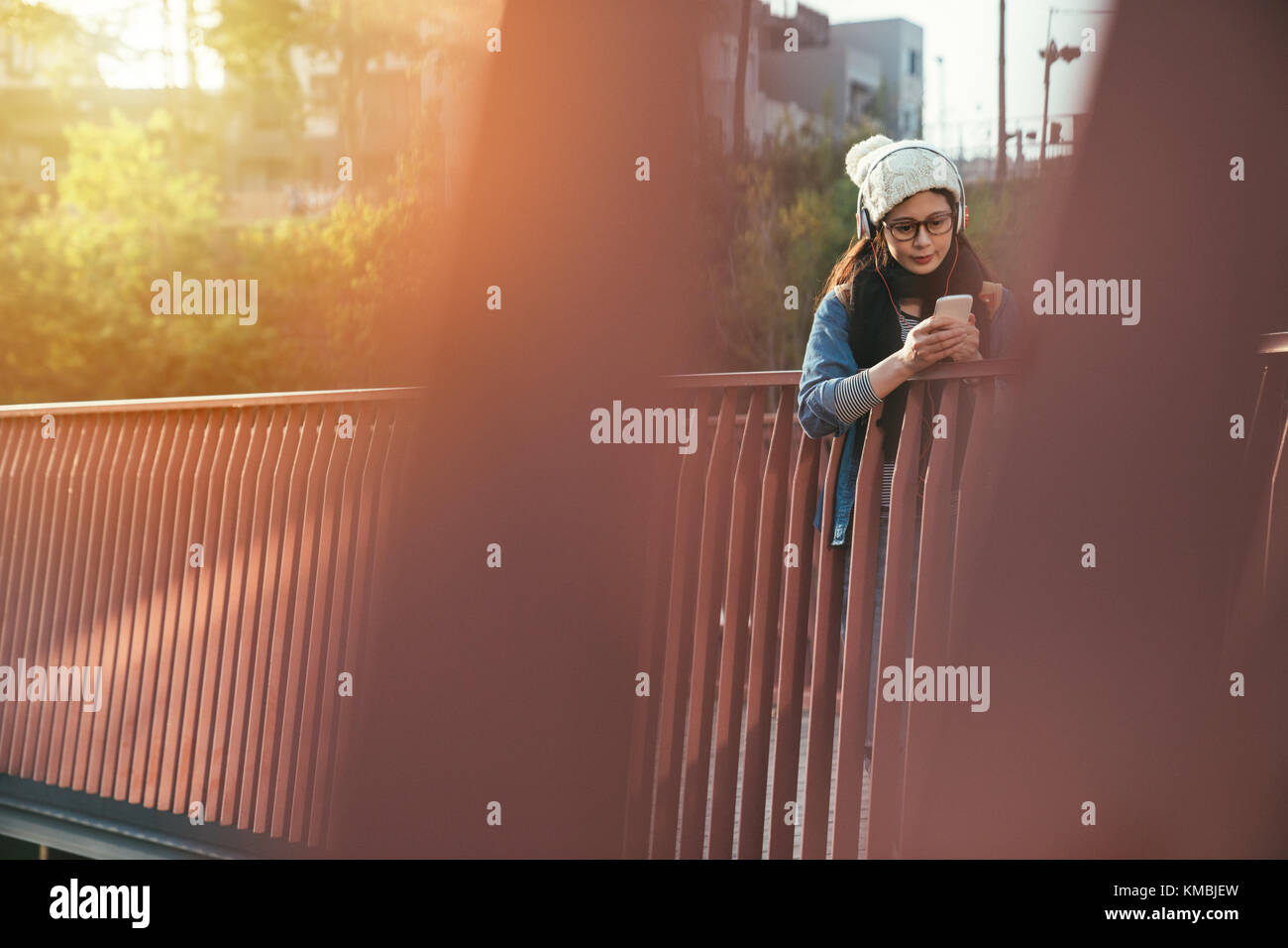 candid shot of beautiful Asian girl student using the smartphone on the river bridge. Stock Photo